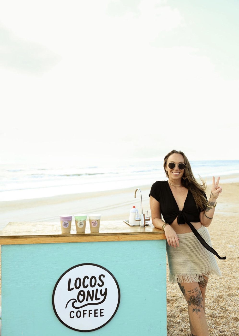 Nikki throwing a peace sign next to the Locos Only cart on the beach